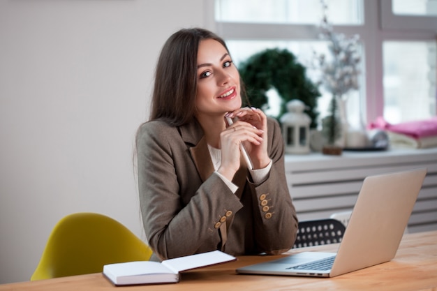 La donna di affari alla moda lavora ad un computer portatile.