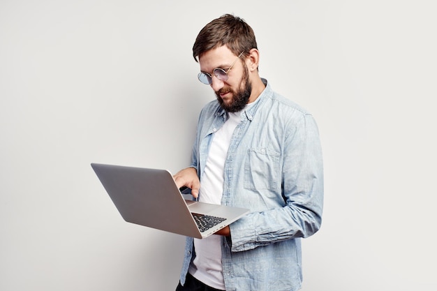 안경을 쓰고 셔츠를 입고 노트북을 들고 흰 벽 배경에 격리된 세련된 백인 남성 프로그래머