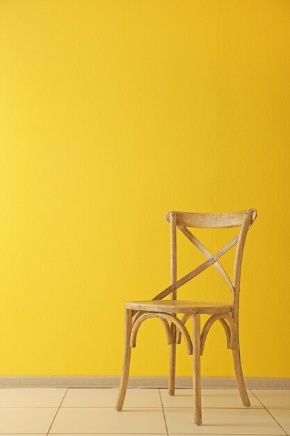 Stylish chair on yellow wall background