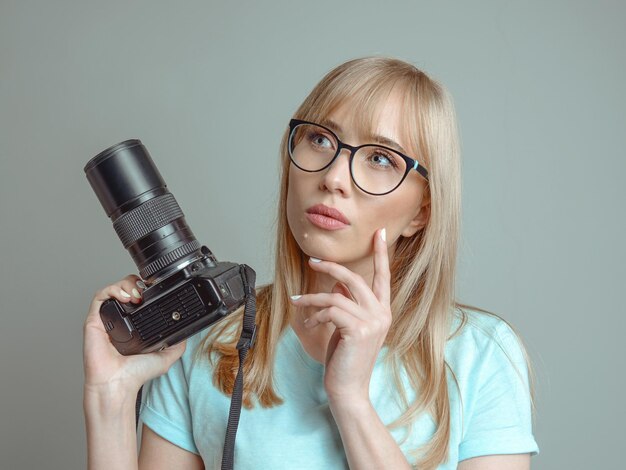 Elegante fotografo donna allegra con gli occhiali e tenendo la macchina fotografica