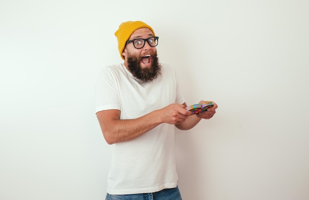 Stylish cheerful young hipster guy with beard plays with a popular toy pop it Anti stress sensory fidget push pop toy