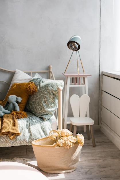 Stylish children's room of the child Wicker basket with flowers pillows on the bed mint and brown