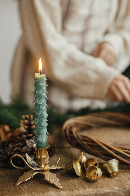 Stylish christmas candle as fir tree and golden bells on rustic wooden table Holiday advent