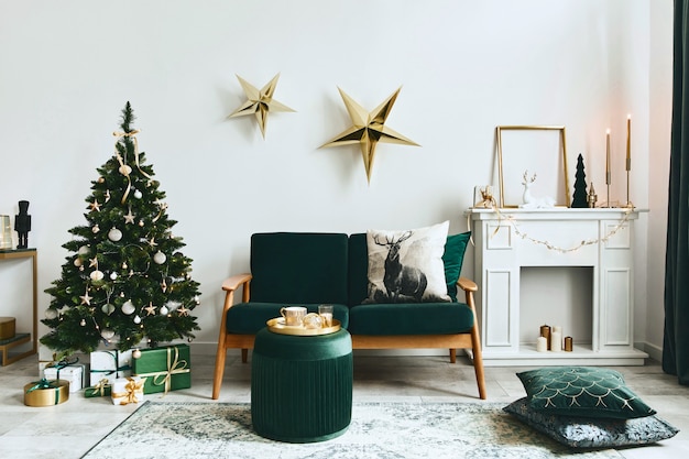 Stylish christmas living room interior with green sofa, white chimney, christmas tree and wreath, stars, gifts and decoration. Family time. Template.