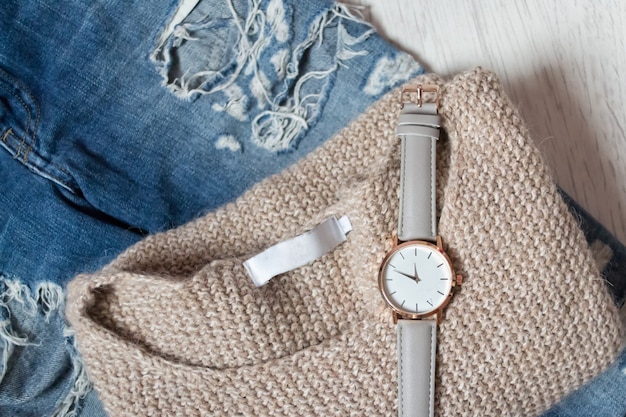 Stylish clock on a sweater and torn jeans