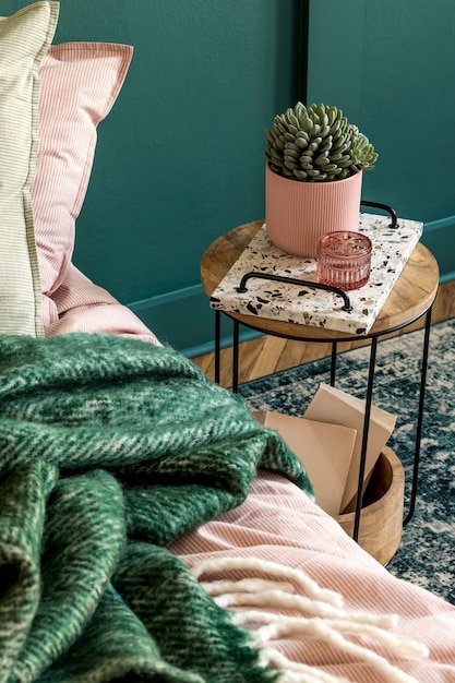 Photo stylish composition of bedroom interior with lastrico tray with coffee and elegant personal accessories. beautiful pink and green bed sheets, blanket and pillow. design home staging. close up