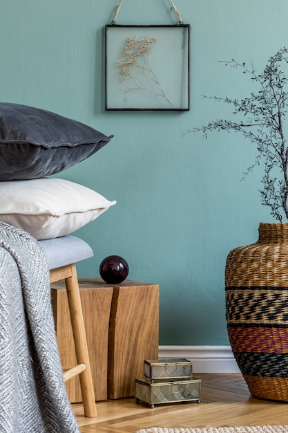 Stylish composition of cozy living room interior details as wooden cube and vase with dry flower and black and white classy velur pillows green walls parquet floor