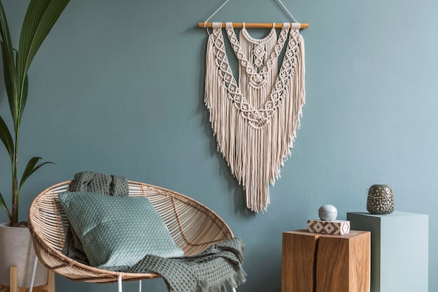 Stylish composition of creative and cozy living room interior with coffee table, rattan armchair, plants, carpet and beautiful boho accessories.