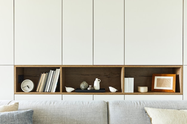 Stylish composition of creative living room interior details such as books, clocks and other personal accessories. white pannels. kitchen on the background. details. template.