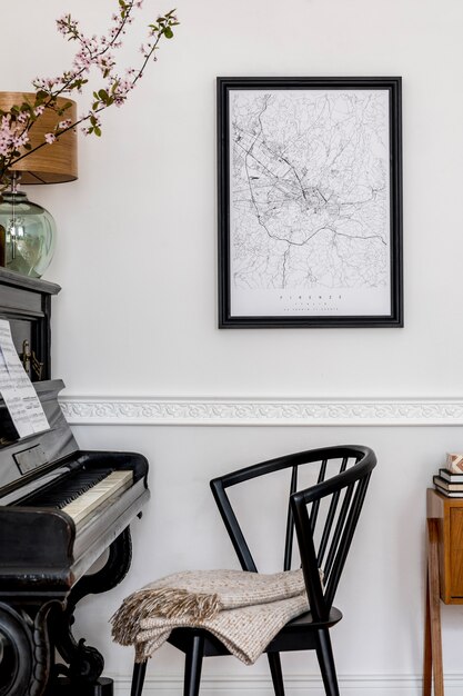 Stylish composition at living room interior with black piano, design chair, black poster map, spring flowers, lamp, furniture and elegant personal accessories in modern home decor.