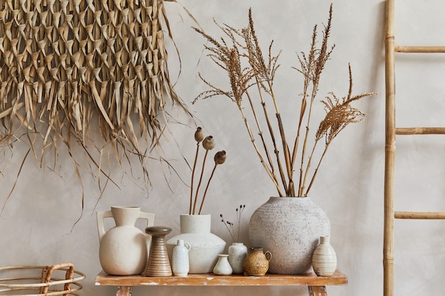 Stylish composition of living room interior with copy space, bench in retro style, clay vases and crockery. Rustic inspiration. Summer vibes. Beige wall. Template.