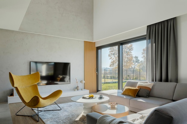 Stylish composition of living room interior with corner beige sofa, yellow armchair, coffee table and minimalist accessories. Panoramic winow. Template.