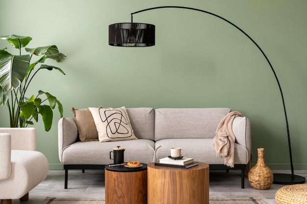 L'elegante composizione all'interno del soggiorno con parete verde design divano grigio tavolino in legno poltrona ed eleganti accessori personali cuscino beige e plaid appartamento accogliente modello