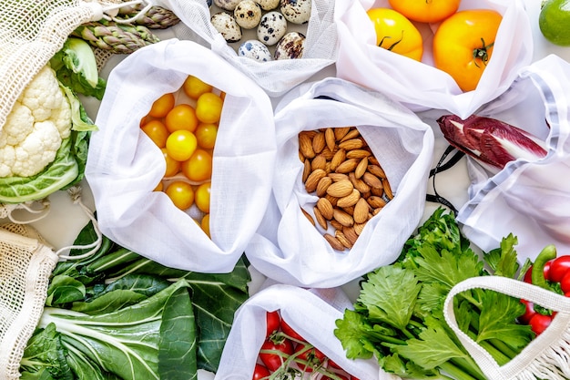 Stylish composition on the marble table with zero waste bags, nuts, seeds, eggs, bio vegetables and eco fruits