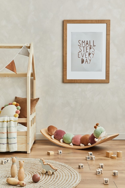 모의 포스터 프레임, 침대, 균형 보드의 플러시 애벌레, 장난감 및 교수형 장식이 있는 아늑한 스칸디 어린이 방 인테리어의 세련된 구성. 창조적 인 벽, 바닥에 카펫. 주형.