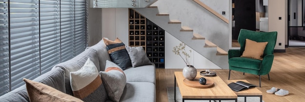 写真 リビングルームのインテリアの階段のスタイリッシュな構成灰色のソファグリーンベルベットアームチェアコーヒーテーブルとミニマリストのパーソナルアクセサリーモダンな家の装飾テンプレート