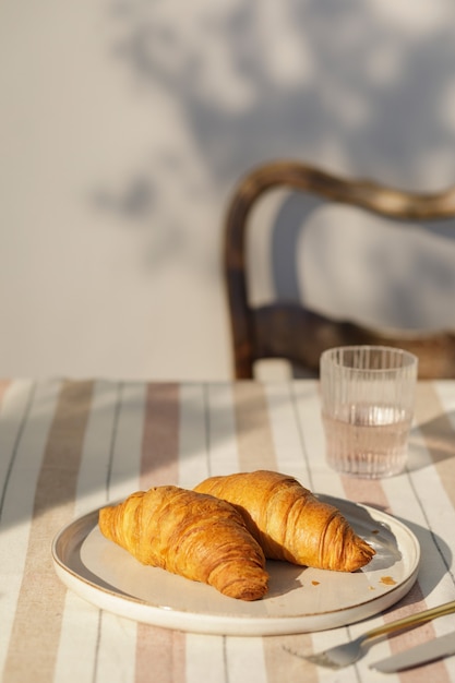 Composizione elegante dello spazio cucina all'aperto con tavolo in legno, cibo, bevande, accessori da cucina, tovaglia beige e ombre estive di alberi. atmosfera di campagna. modello.