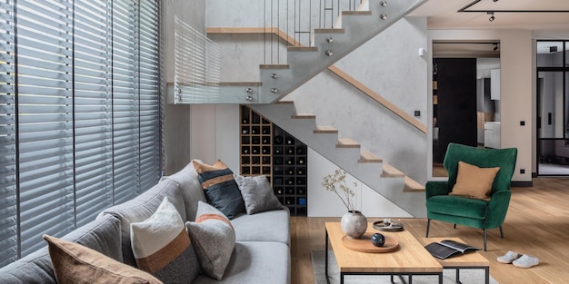 Foto elegante composizione di scale nell'interno del soggiorno divano grigio poltrona in velluto verde tavolino e accessori personali minimalisti modello di arredamento per la casa moderno