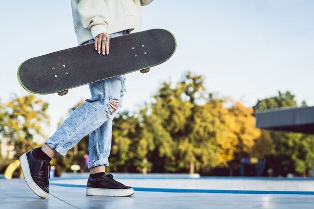 Stylish cool teen female skateboarder at skate park