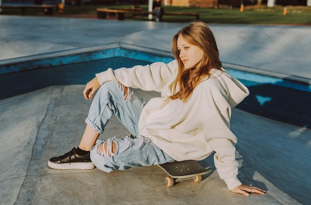 Stylish cool teen female skateboarder at skate park