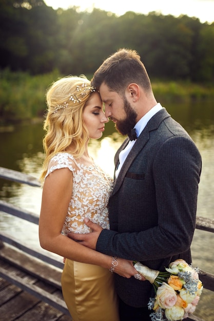 Stylish couple of happy newlyweds posing in the park on their wedding day Perfect couple bride groom