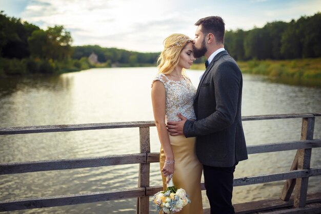 Stylish couple of happy newlyweds posing in the park on their wedding day