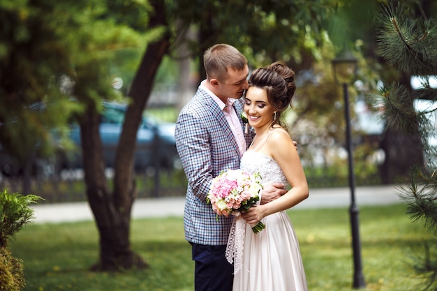 Stylish couple of happy newlyweds posing on their wedding day. Perfect couple bride, groom posing and kissing