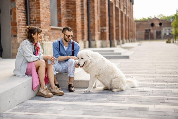 Stylish couple have fun and sit with their dog on a street