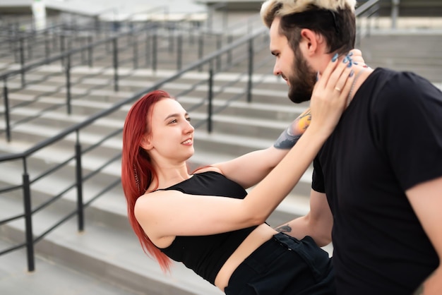 Stylish couple in love in black clothes walks in the park and\
hugs lovely couple of hipsters hugging on the background of the\
stairs youth love and lifestyle concept