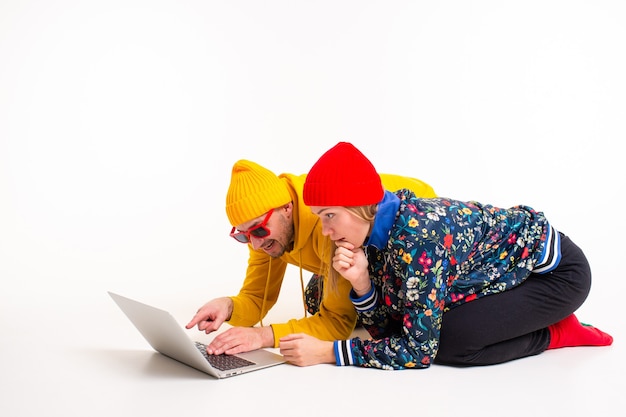 Stylish couple of man and woman in colorful clothes looking at the screen of laptop