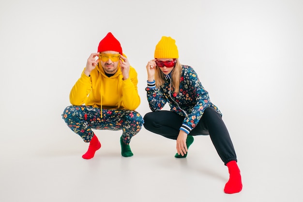 Stylish couple of man and woman in colorful clothes posing over white wall