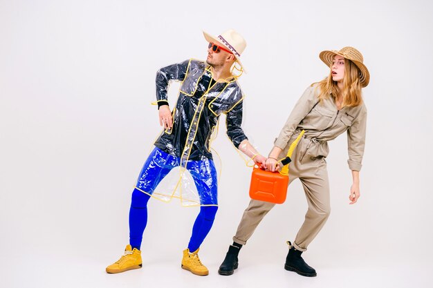 Stylish couple of man and woman in straw hats posing with watering pot