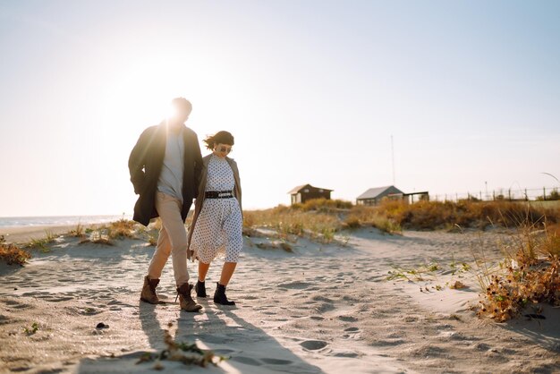 写真 スタイリッシュなカップルが海辺を歩いて抱きしめています 春のリラックス 青年の愛のライフスタイル