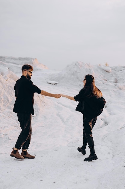 Stylish couple walking and hugging walking in a background of white mountains