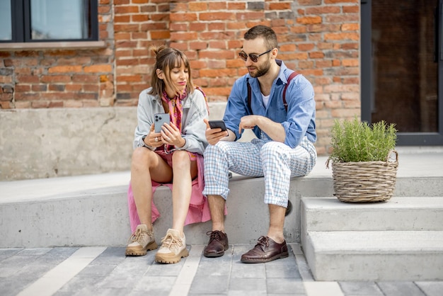 Stylish couple with phones outdoors