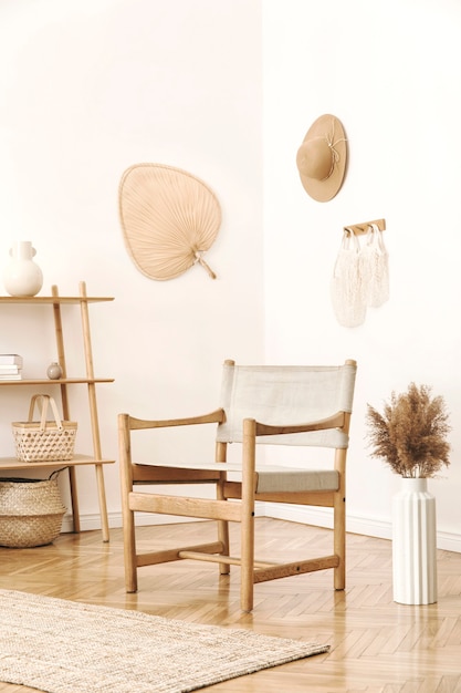 Stylish and cozy interior of living room with rattan accessories, design armchair, flowers in vase and wooden shelf. Korean style of home decor.