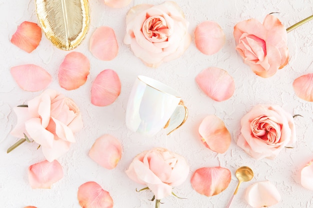 Stylish Cup of coffee, leaf golden plate and spoon with pink roses flowers and petals