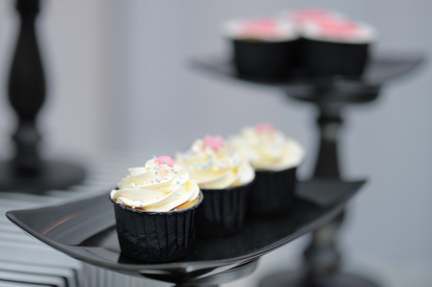 Stylish cupcakes on black glass plate