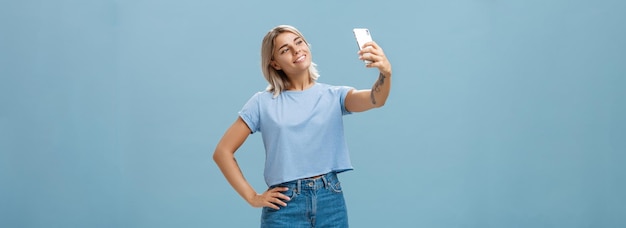 Foto elegante e carina direttrice di una palestra che si fa un selfie con il nuovo smartphone posando con un ampio sorriso soddisfatto