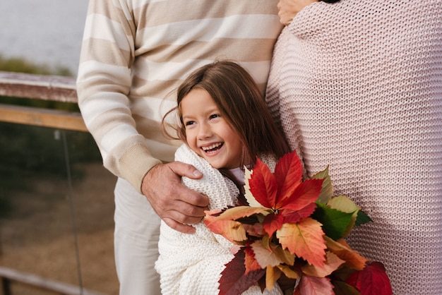 Стильный папа обнимает маму и дочку с букетом цветов