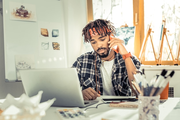 Photo stylish designer. stylish interior designer wearing squared shirt and red headband speaking by phone