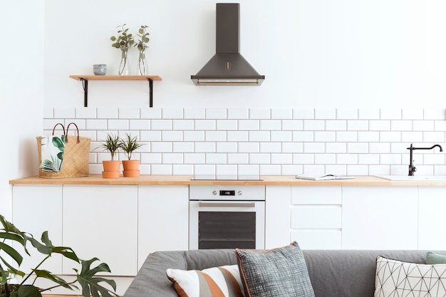 Stylish details of creative kitchen interior in scandinavian apartment with basket tiny plants and other accessoires White creative wall wooden furniture