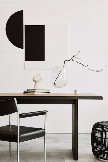 Foto interni eleganti della sala da pranzo con tavolo da famiglia in legno di design, sedie nere, teiera con tazza, dipinti d'arte sul muro e accessori eleganti in un arredamento moderno per la casa modello