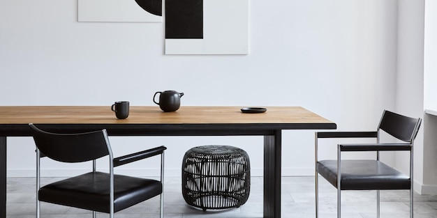 Стильный интерьер столовой с дизайнерским деревянным семейным столом, черными стульями, чайником с кружкой, макетами художественных картин на стене и элегантными аксессуарами в современном домашнем декоре. Шаблон.