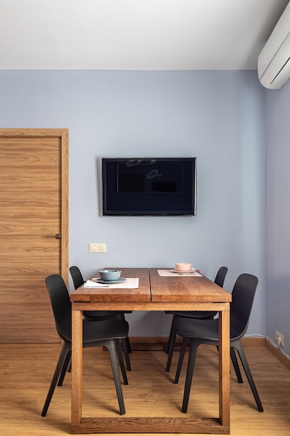 Stylish dining room interior with wooden table black chairs and tv set