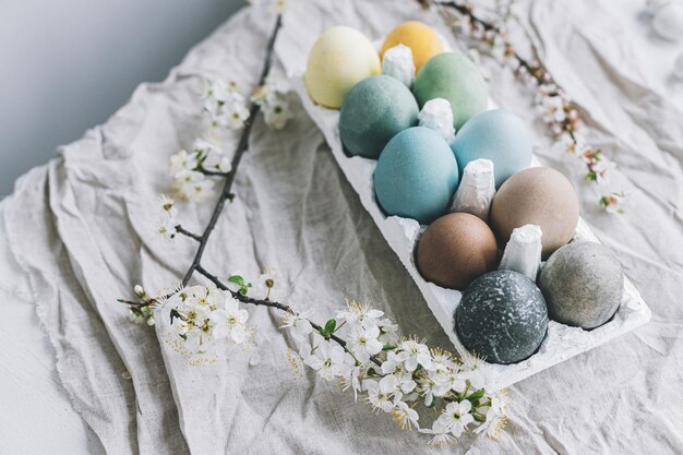 Stylish Easter eggs and cherry blossoms on rustic linen cloth Happy Easter