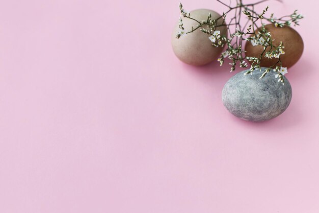 ピンクの背景にスタイリッシュなイースターエッグと花 モダンな自然染めの卵と花のボーダー
