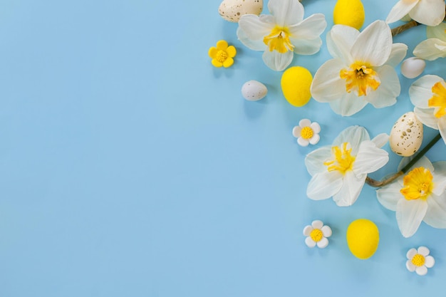 세련된 부활절 달걀과 노란 수선화 꽃은 복사 공간이 있는 파란색 배경에 평평하게 놓여 있습니다. 행복한 부활절 인사말 카드 템플릿 현대적인 휴일 배너 축제 구성