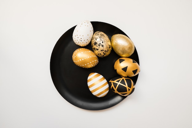Stylish Easter golden decorated eggs on black plate 