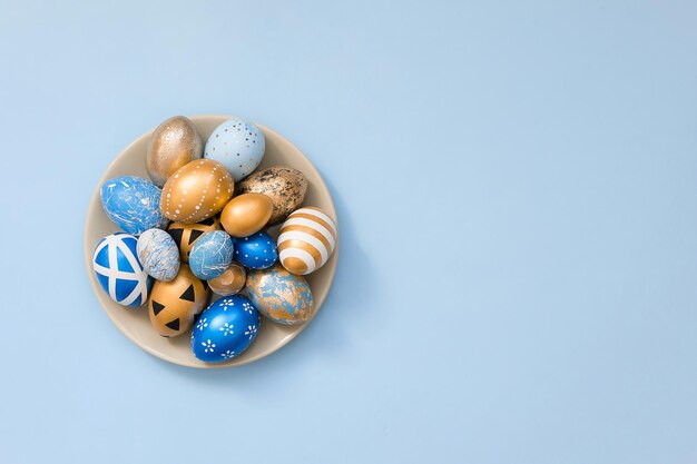 Stylish easter golden decorated eggs on grey plate isolated on blue background